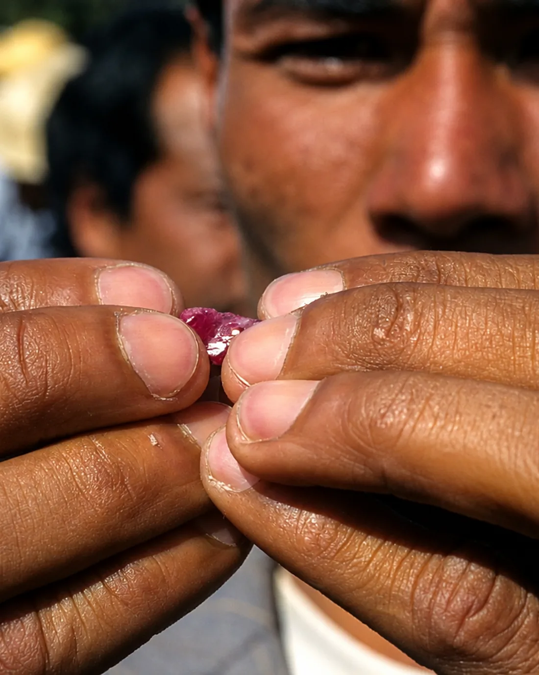A miner holds a rough ruby to the light at Mogok