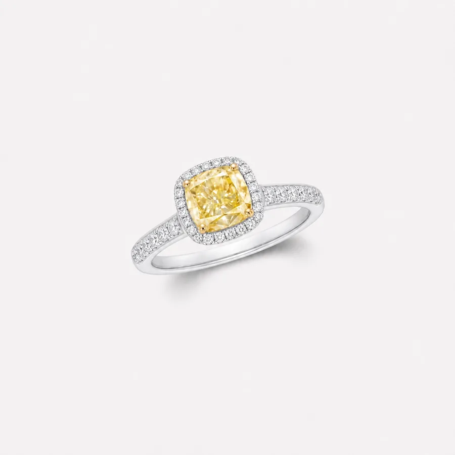 Fancy yellow cushion-cut diamond engagement ring with a halo of brilliants on a white gold pavé band
